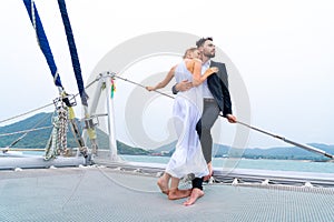 Luxury relaxing couple traveler in nice dress and suite stand at part of cruise yacht with background of water sea and white sky.