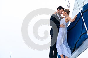 Luxury relaxing couple traveler in nice dress and suite stand at part of cruise yacht with background of water sea and white sky.