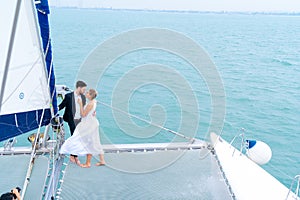 Luxury relaxing couple traveler in nice dress and suite stand at part of cruise yacht with background of water sea and white sky.