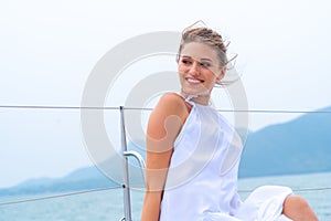 Luxury relaxing girl traveler in nice dress and suite sit at part of cruise yacht with background of sea and white sky. Concept