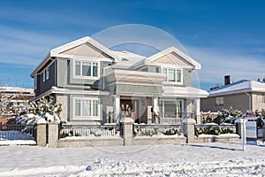 Luxury residential house with front yard in snow on winter sunny day
