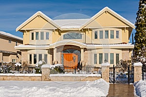 Luxury residential house with front yard in snow on winter sunny day