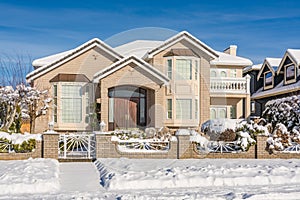 Luxury residential house with front yard in snow on winter sunny day