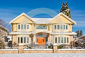 Luxury residential house with front yard in snow on winter sunny day