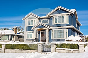 Luxury residential house with front yard in snow on winter sunny day