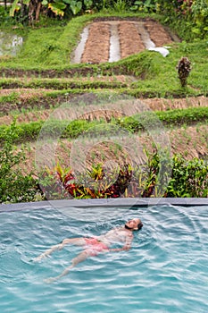 Luxury Resort. Man Relaxing In Infinity Swimming Pool Water. Beautiful Happy Healthy Male Model Enjoying Summer Travel