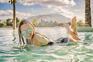 Luxury resort swimming pool. Beautiful woman tourist relaxing in holiday retreat on summer travel vacation. Bikini girl