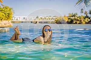 Luxury resort swimming pool. Beautiful woman tourist relaxing in holiday retreat on summer travel vacation. Bikini girl