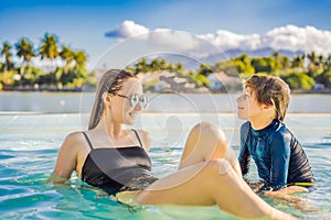 Luxury resort swimming pool. Happy family tourists relaxing in holiday retreat on summer travel vacation enjoying ocean