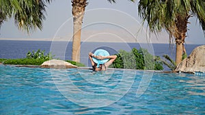 Luxury Resort. Woman Relaxing In Infinity Swimming Pool Water. Beautiful Happy Healthy Female Model Enjoying Summer