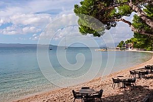 Luxury restaurant on idyllic beach in coastal town Makarska, Split-Dalmatia, Croatia, Europe. Scenic view of sailing boat