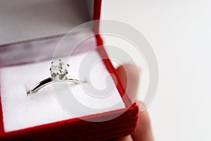 Luxury ring with diamond in stylish red box in hand on white bac