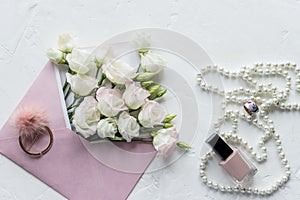 Luxury romantic background: white flowers, pearls necklace, perfume, greeting card on white.accessories and flowers