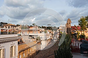 Luxury rooftop terrace at hotel in Rome with red chairs, tables, and plants overlooking cityscape.