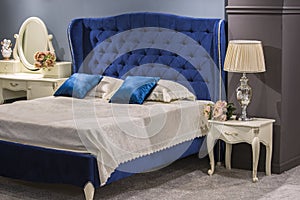 Luxury royal bedroom in antique style with blue velvet bed and white nightstand