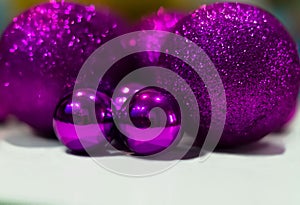 Luxury, shiny, large and small purple Christmas balls close-up on a white table at home. Bright Christmas decorations. Selective f