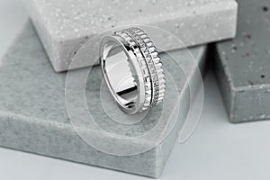 Luxury silver wedding ring with diamonds and geometric shapes on gray background