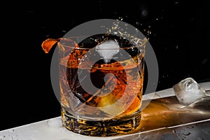 Luxury still life of whiskey glass, on the rocks, with ice cube falling into Glass of Whisky, Freeze Motion.Copy space. Splash