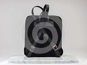 Luxury suet backbag. Luxury black leather and suet backpack on white background, on marble floor.