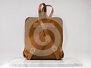 Luxury suet backbag. Luxury orange leather and suet backpack on white background, on marble floor.