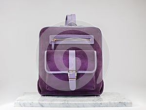 Luxury suet backbag. Luxury purple leather and suet backpack on white background, on marble floor.