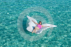 Luxury summer vacation beach woman relaxing lying down on inflatable pool float floating at Maldives sun tanning. Model sleeping o