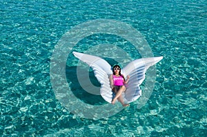 Luxury summer vacation beach woman relaxing lying down on inflatable pool float floating at Maldives sun tanning. Model sleeping o