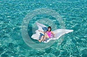 Luxury summer vacation beach woman relaxing lying down on inflatable pool float floating at Maldives sun tanning. Model sleeping o