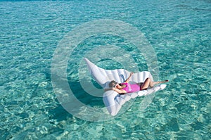 Luxury summer vacation beach woman relaxing lying down on inflatable pool float floating at Maldives sun tanning. Model sleeping o