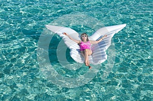 Luxury summer vacation beach woman relaxing lying down on inflatable pool float floating at Maldives sun tanning. Model sleeping o