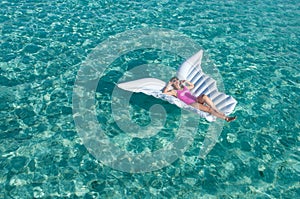 Luxury summer vacation beach woman relaxing lying down on inflatable pool float floating at Maldives sun tanning. Model sleeping o