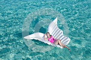 Luxury summer vacation beach woman relaxing lying down on inflatable pool float floating at Maldives sun tanning. Model sleeping o