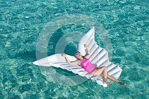 Luxury summer vacation beach woman relaxing lying down on inflatable pool float floating at Maldives sun tanning. Model sleeping o