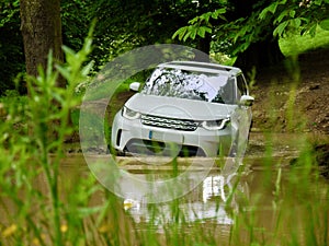 Luxury SUV 4x4 off-roading through a pond.