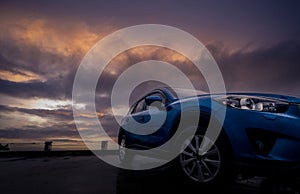 Luxury SUV car with raindrops. Front view new blue SUV car parked on concrete parking lot near sea beach with sunset sky. Electric