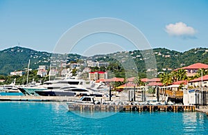 Luxury travel on boat, water transport. Yachts moored at sea pier on mountain landscape. Sea port and town on sunny blue