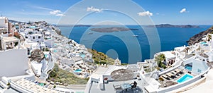 Luxury travel destination in Santioni island, Greece. White houses and caldera sea view with loungers under blue sky, romance