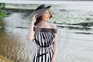 Luxury travel woman in black and white beachwear walking taking a stroll on sand summer beach. Girl tourist on summer