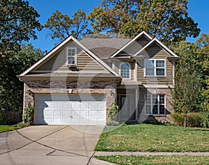 Brown Brick & Vinyl Sided Home with Arched Window in Fall