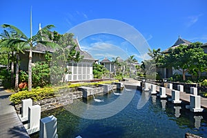 Luxury upscale resort hotel with water flowing into pond surrounded by bungalows