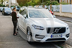 Luxury Volvo XC90 parked on French city with owner approaching