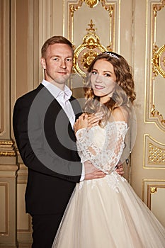 Luxury wedding couple in love. Beautiful bride in white dress with brides bouquet and handsome groom in black suit