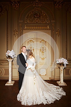 Luxury wedding couple in love. Beautiful bride in white dress with brides bouquet and handsome groom in black suit