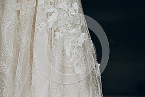 Luxury wedding dress detail, hanging on window in a hotel room.