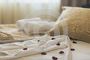 Luxury wellness and spa hotel room arranged for romantic weekend. Honeymoon suite bedroom decorated with rose petals on bed sheets