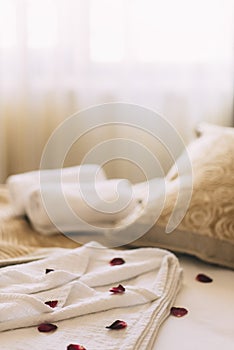 Luxury wellness and spa hotel room arranged for romantic weekend. Honeymoon suite bedroom decorated with rose petals on bed sheets