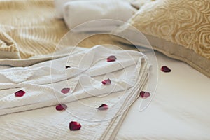Luxury wellness and spa hotel room arranged for romantic weekend. Honeymoon suite bedroom decorated with rose petals on bed sheets