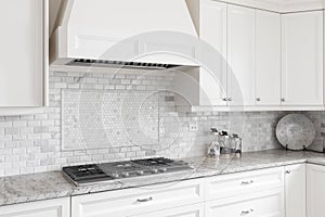 A luxury white kitchen`s stovetop and hood.