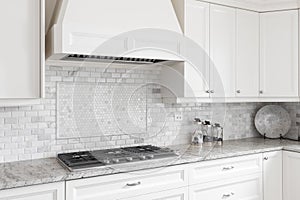 A luxury white kitchen`s stovetop and hood. photo