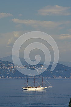 Luxury white sailboat in Portofino with sea, mountains, cliffs and villas.